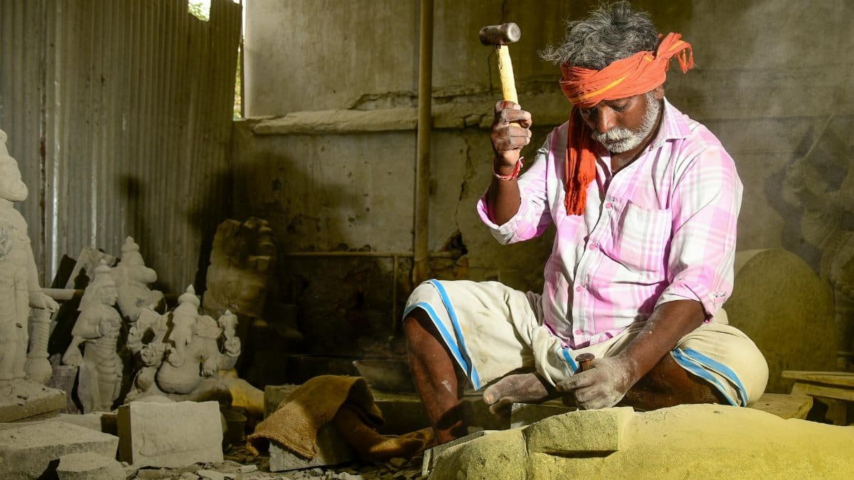 A skilled artisan crafting a stone sculpture in a traditional workshop setting.