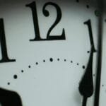 Macro photograph of a clock face showing numbers and minute markers.