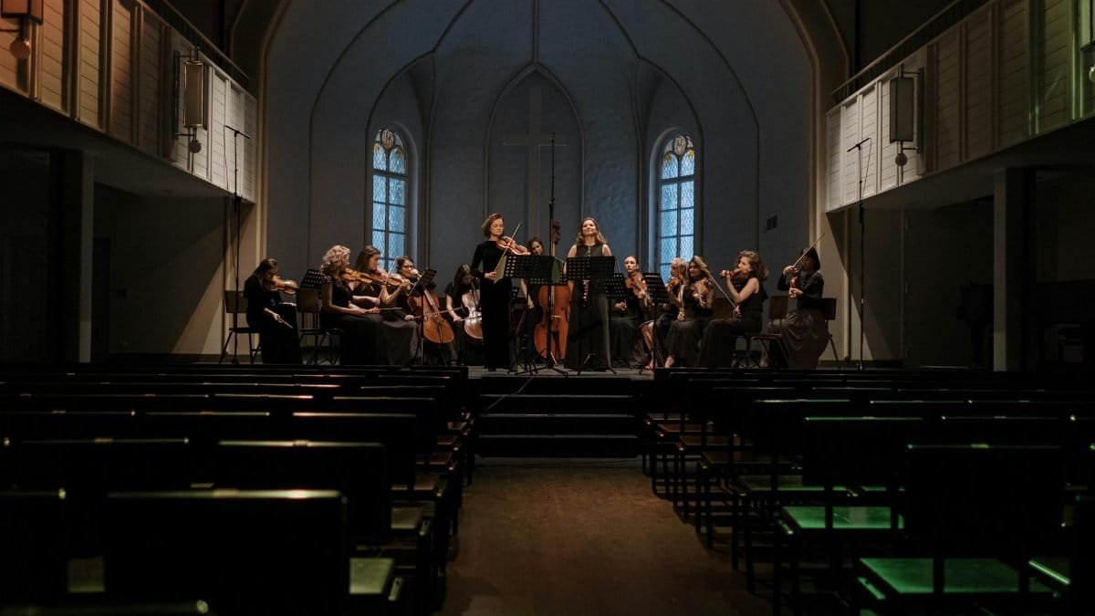 An orchestra rehearsing in a church, blending religious architecture with classical music.