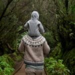 A father carrying his child on a forest path, enjoying nature and bonding on an autumn day.