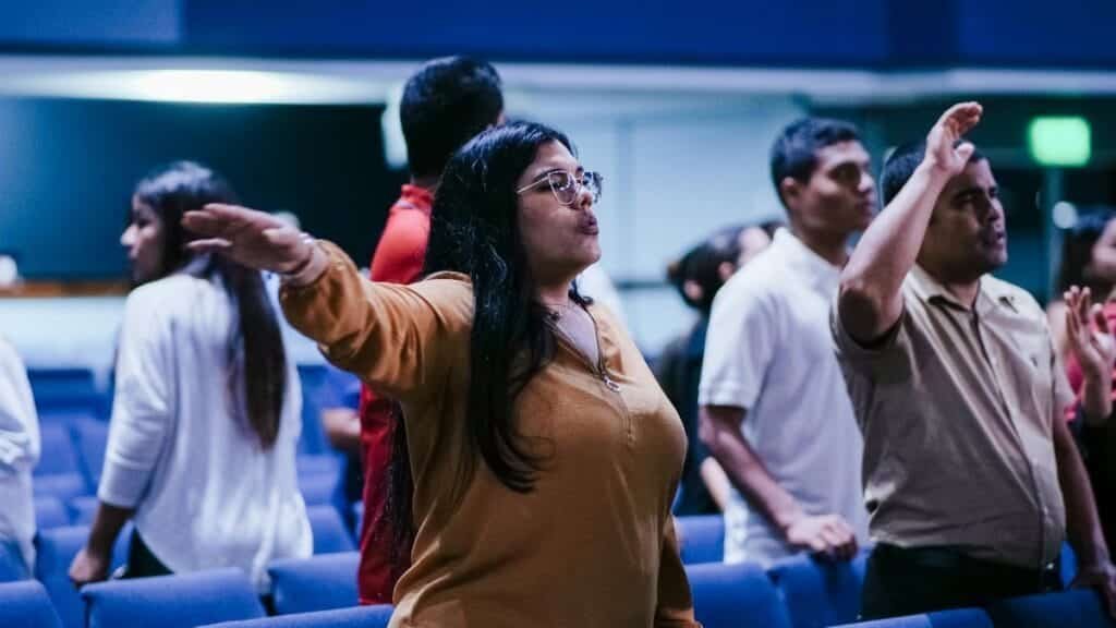 Group of people attending a religious gathering in a church, engaging in worship and prayer.