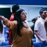 Group of people attending a religious gathering in a church, engaging in worship and prayer.