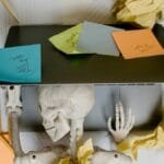 A striking visual of a skeleton at a laptop surrounded by notes and paper, symbolizing work burnout.