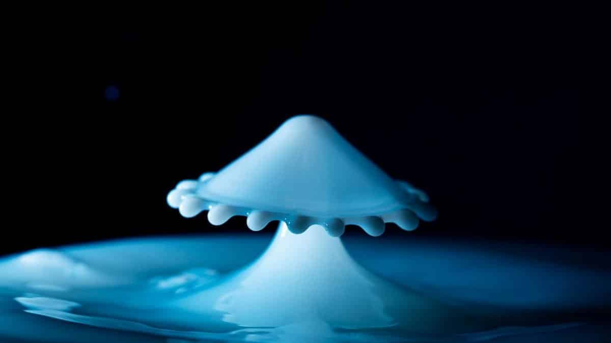 Close-up of a milk drop splash creating an abstract shape with dramatic blue lighting.