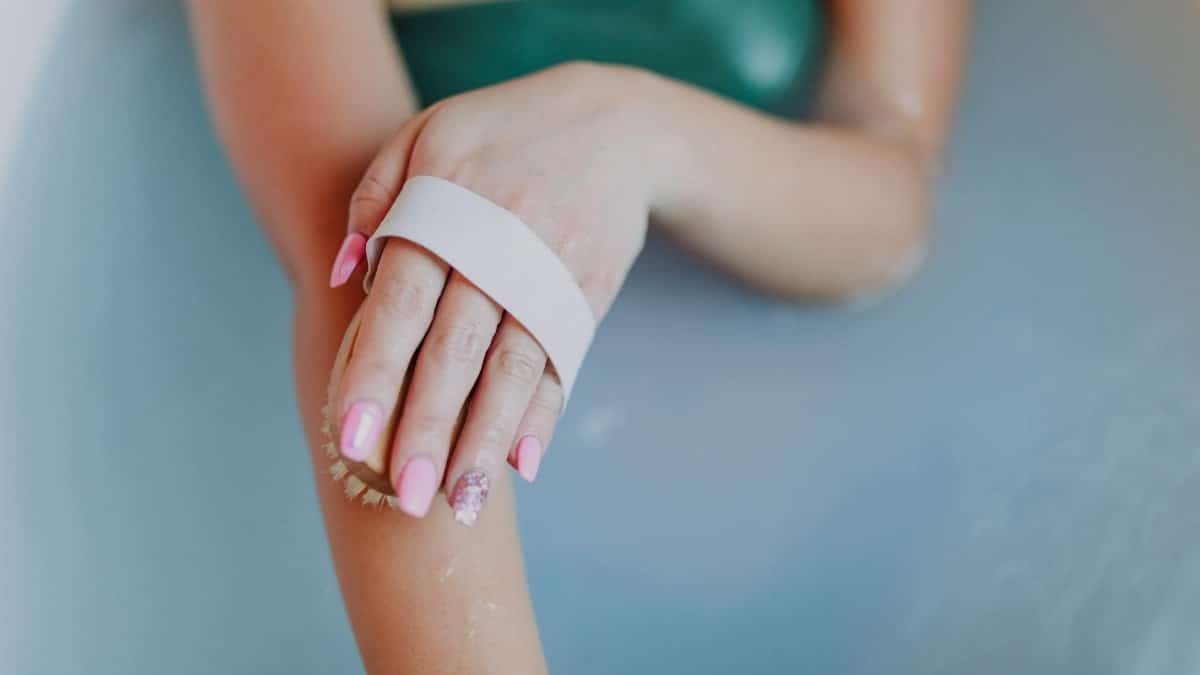 A woman enjoys a relaxing bath, focusing on self-care with a body scrub brush.
