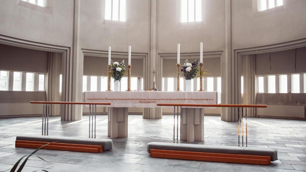 A spacious modern church altar with candles, flowers, and natural light.
