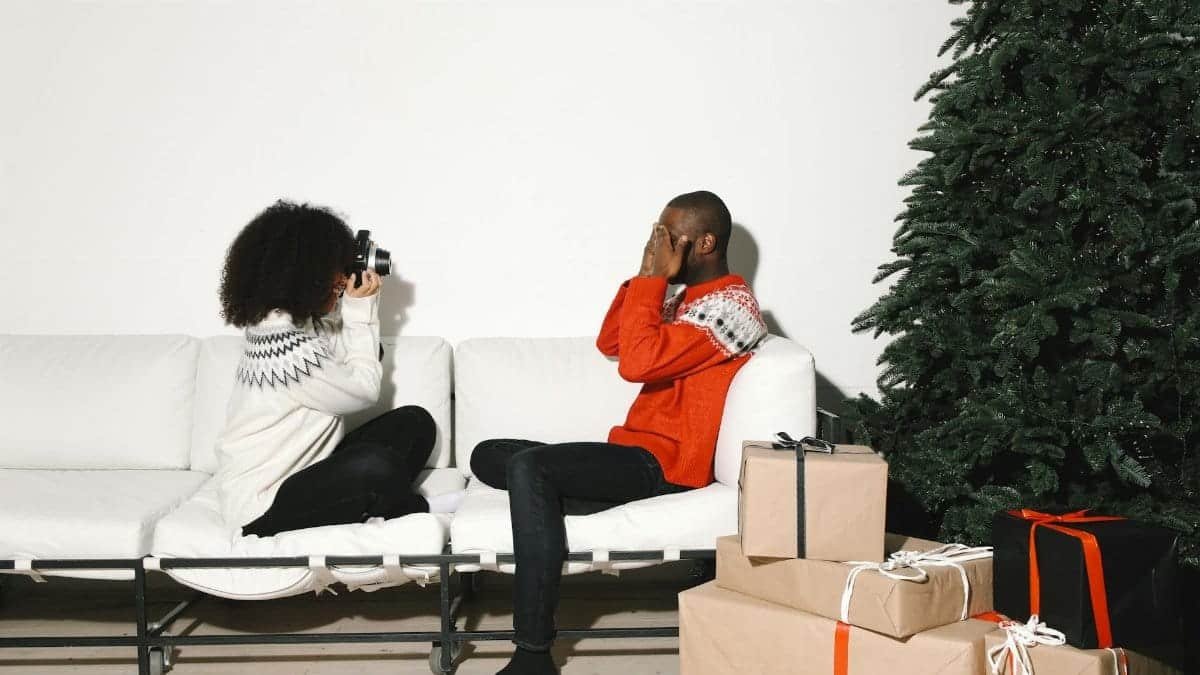 Joyful indoor holiday scene featuring a couple by a Christmas tree with gifts. Ideal for festive and lifestyle imagery.