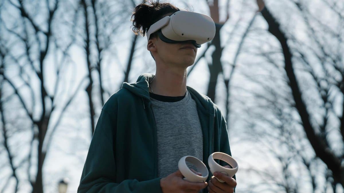 Anonymous male in virtual reality headset enjoying game on blurred background of leafless trees