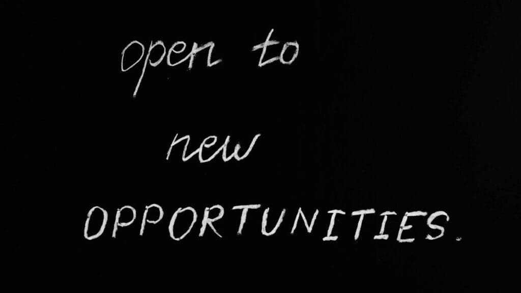 Blackboard with motivational quote 'Open to New Opportunities' in chalk writing.