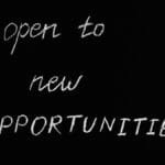Blackboard with motivational quote 'Open to New Opportunities' in chalk writing.