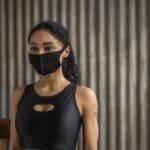 Portrait of a young woman in activewear with a face mask, embodying the new normal indoors.