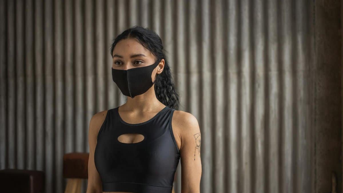 Portrait of a young woman in activewear with a face mask, embodying the new normal indoors.