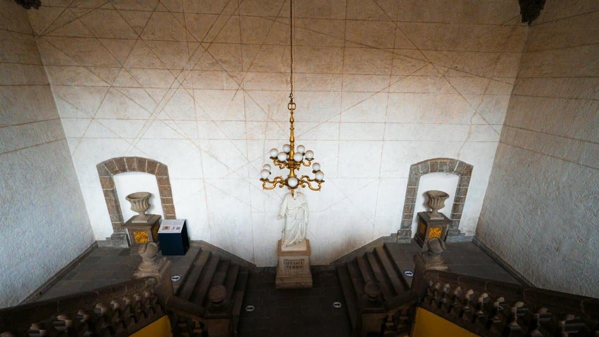 Majestic museum staircase in Mexico City with grand chandelier and statue.