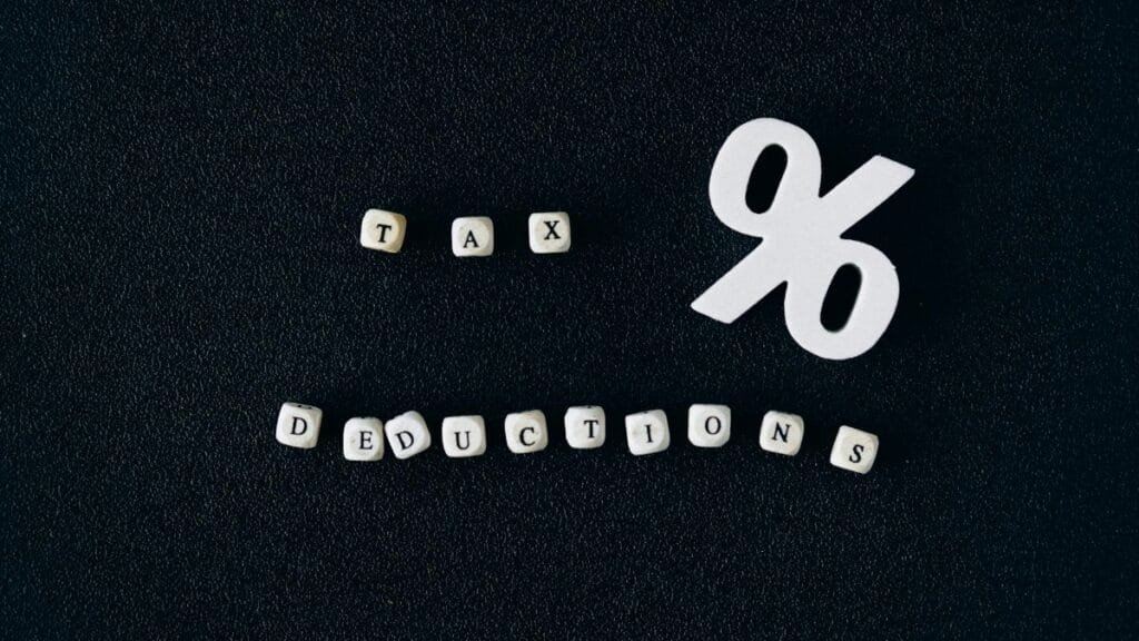 Conceptual image of tax deductions with alphabet blocks and percent symbol on black surface.