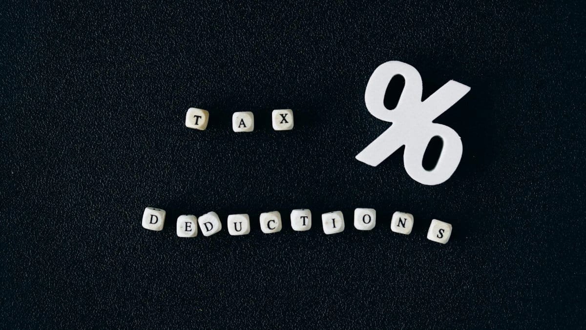 Conceptual image of tax deductions with alphabet blocks and percent symbol on black surface.