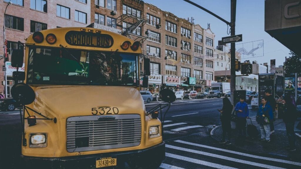 Yellow school bus on a bustling city street with pedestrians in New York.