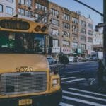 Yellow school bus on a bustling city street with pedestrians in New York.