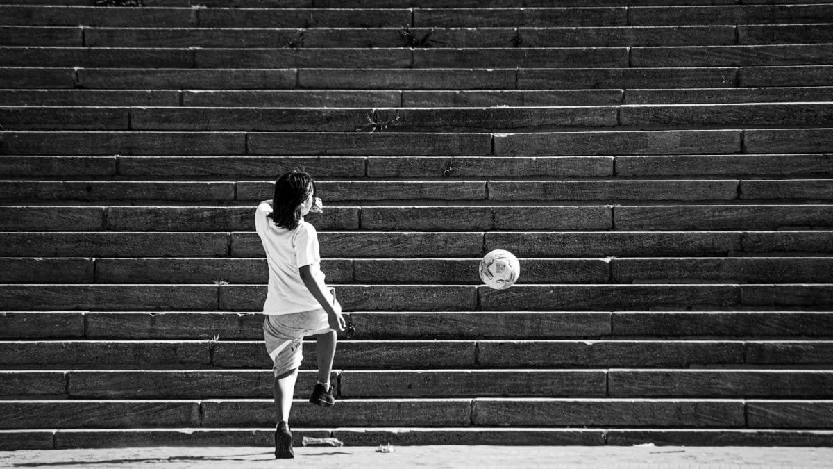 Black and white photo of a boy playing with a ball on steps in Mar del Plata, Argentina.
