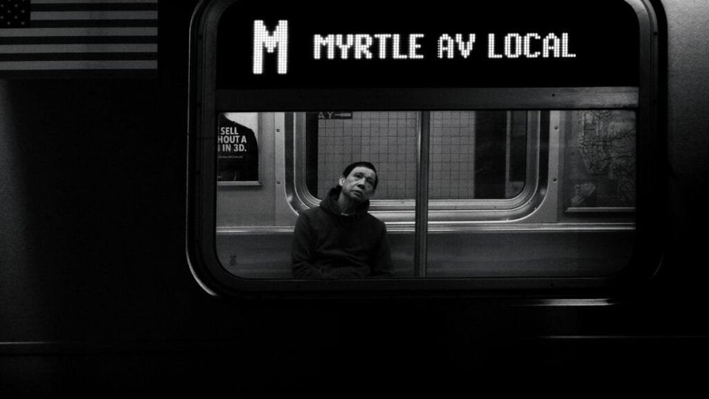 Black and white photo capturing a commuter in deep thought on the NYC Subway.