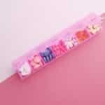 A pink pill organizer with colorful tablets arranged for each day of the week on a vibrant pink background.