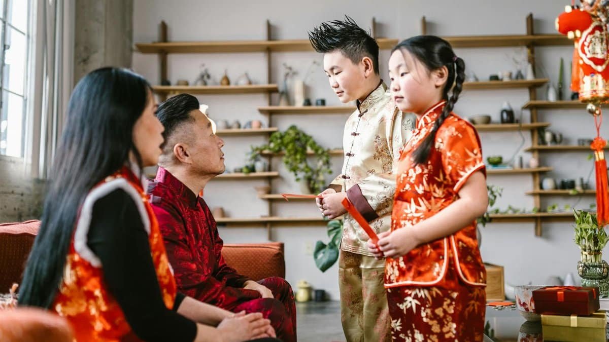 Asian family exchanging red envelopes during Lunar New Year celebration indoors.