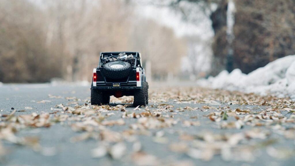Miniature toy car on an autumn road with scattered leaves, showcasing detail and seasonal charm.