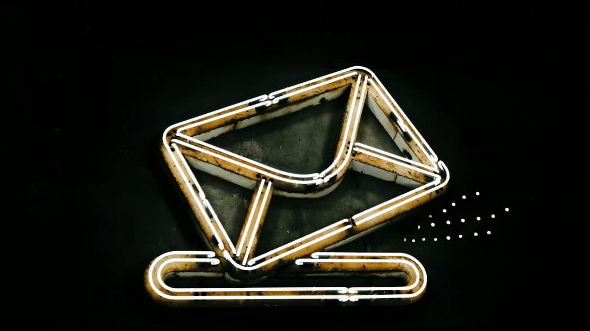 A glowing neon envelope symbol against a black background, conveying messaging or email concept.