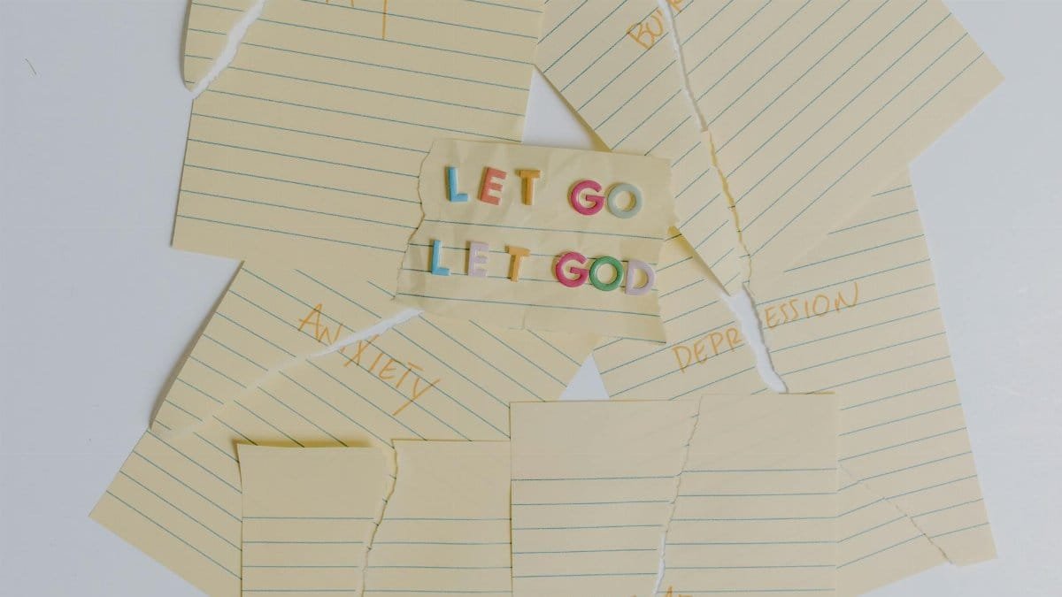 Flat lay of torn notes with an inspirational 'Let Go, Let God' message.
