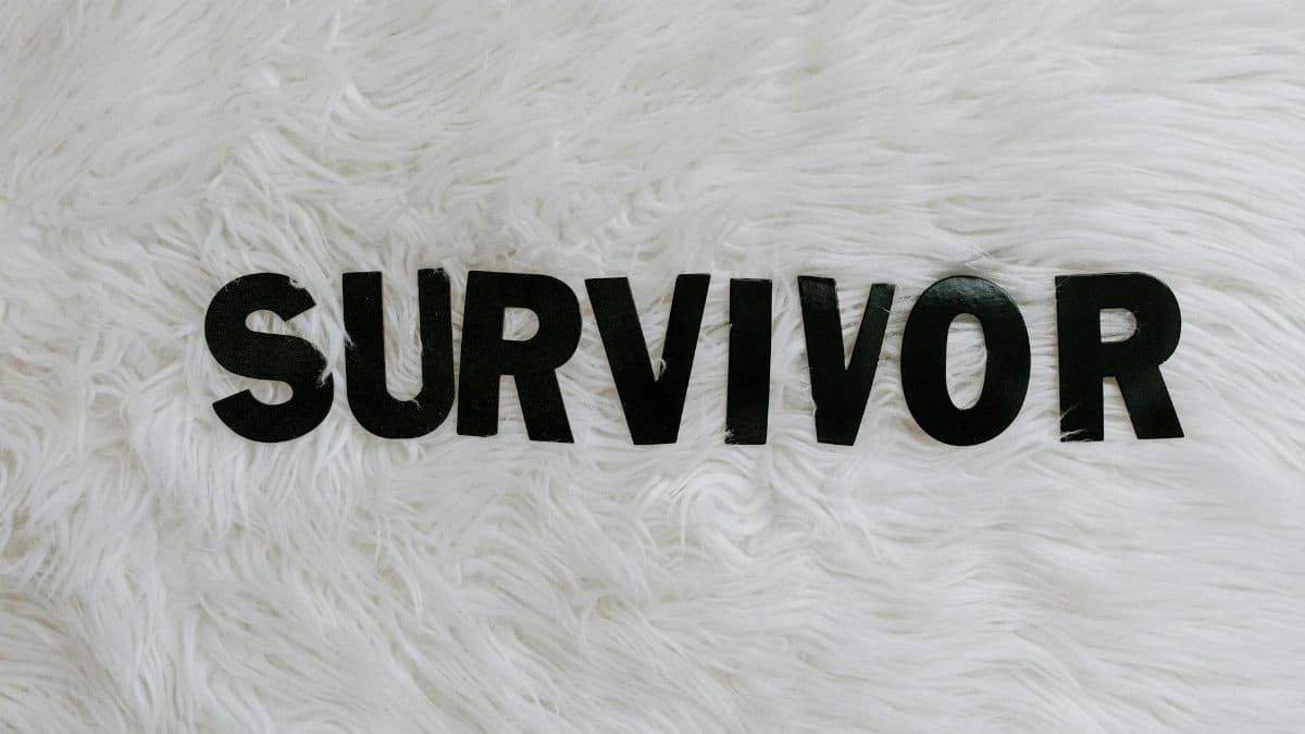 Black letters spelling 'SURVIVOR' on a white textured surface, symbolizing resilience.