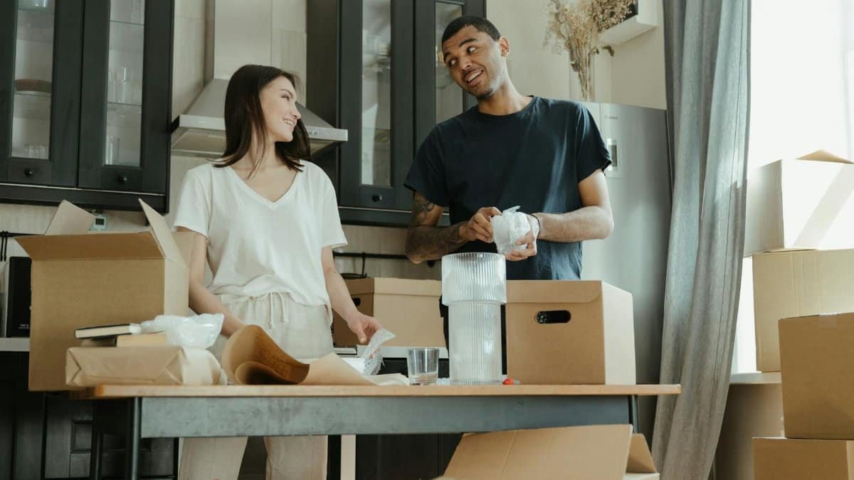 Smiling couple unpacking boxes in their new home kitchen, ready for a fresh start.