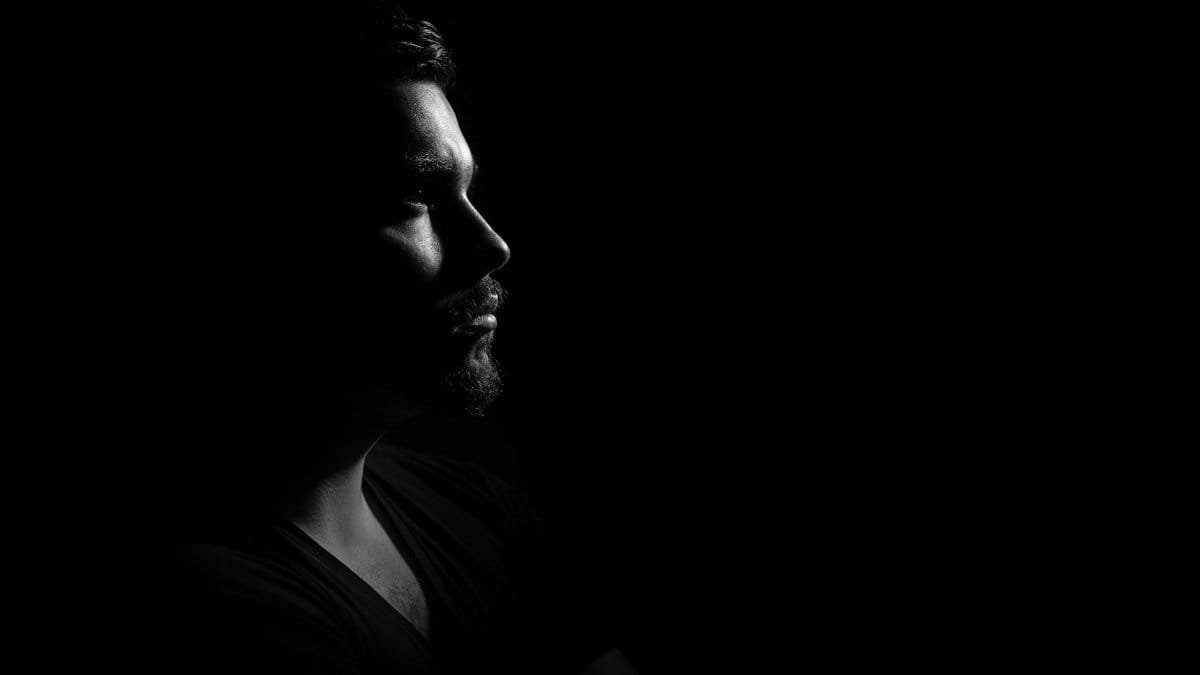 Profile portrait of a man in black and white, emphasizing shadows and highlights.
