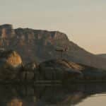 Woman practicing yoga on boulders during sunset in Cape Town, reflecting a serene wellness moment.