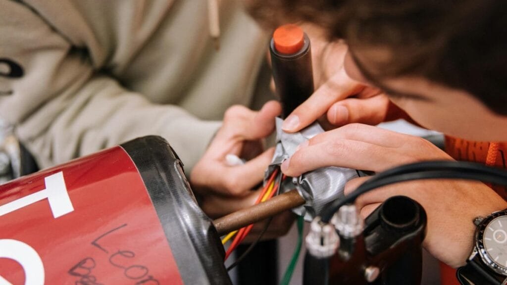 Two teenagers work on wiring as part of a STEM educational project indoors.