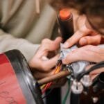 Two teenagers work on wiring as part of a STEM educational project indoors.