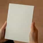 A person holding a blank hardcover book. Perfect for mockup and design templates.
