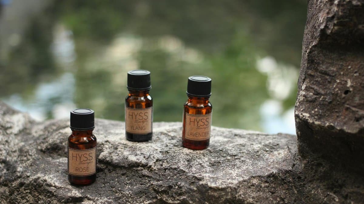 Three essential oil bottles labeled Hyss on a rustic stone surface, outdoors.