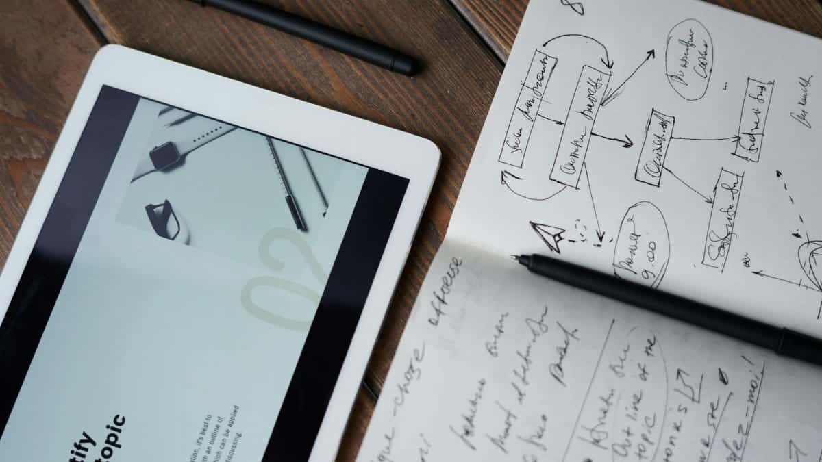 Digital and handwritten brainstorming tools on a wooden desk, ideal for business and study contexts.