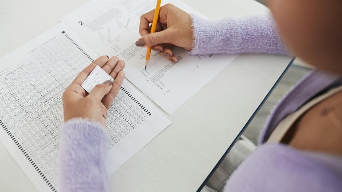 Close-up of a student using a cheat sheet during an exam, illustrating academic dishonesty.