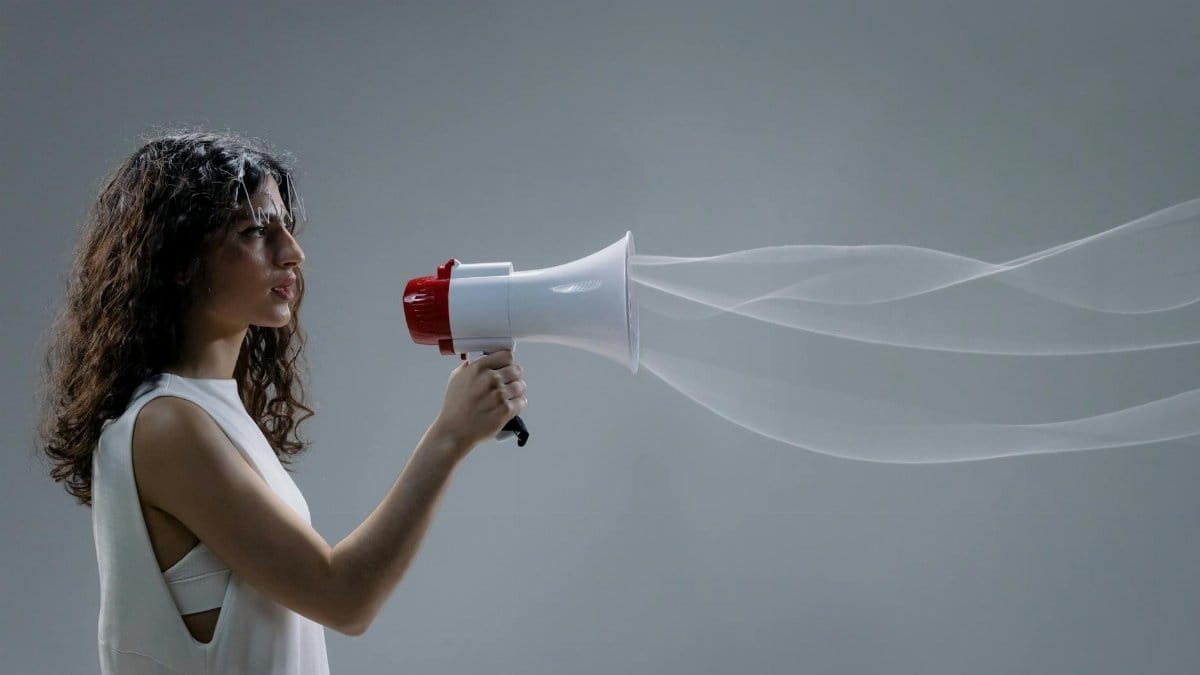 Woman using a megaphone emitting sound waves on a gray background.