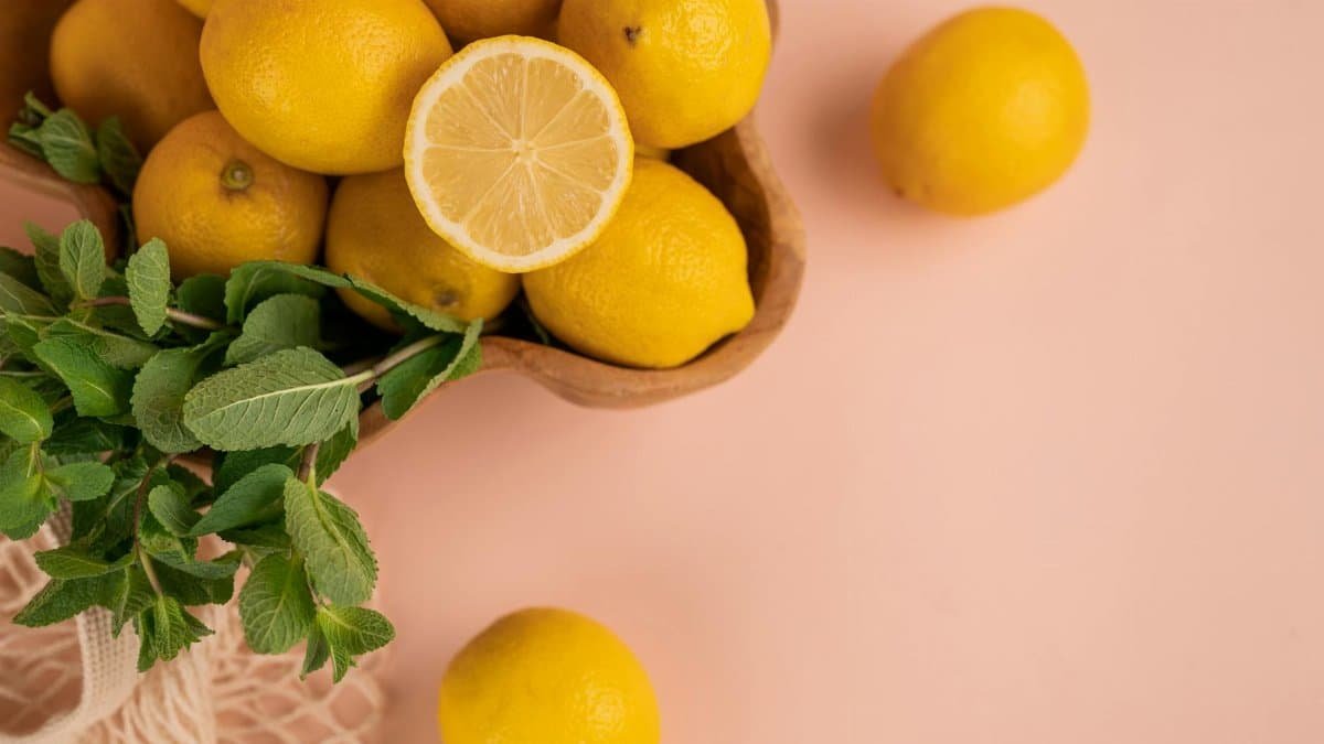 Bright and fresh lemons with mint leaves on a pastel background, perfect for culinary themes.
