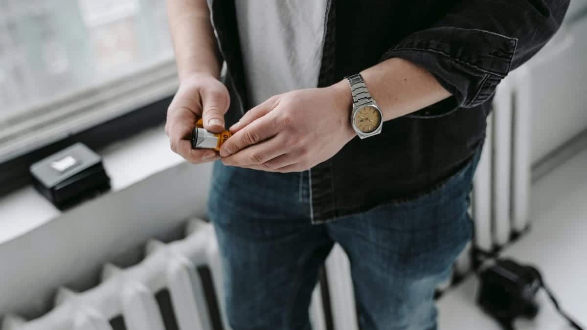 A person holding a film cartridge inside an urban setting, emphasizing analog photography.