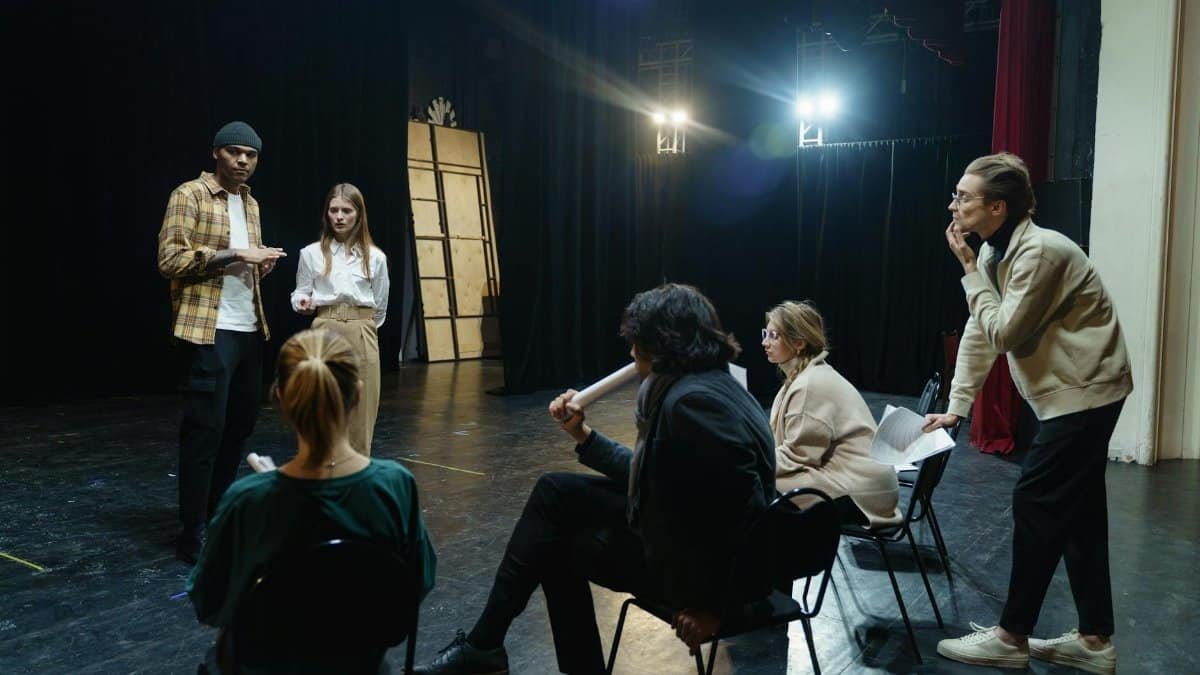 Actors rehearsing on stage with director's guidance in a theater for a live performance.