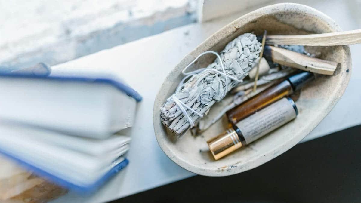 A calming arrangement of healing crystals, sage, and essential oils on a windowsill for spiritual rituals.