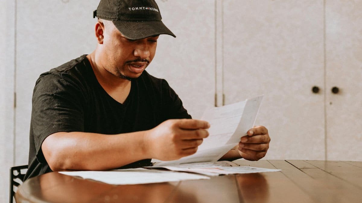 Adult man sitting at home table, focused on reviewing important documents.
