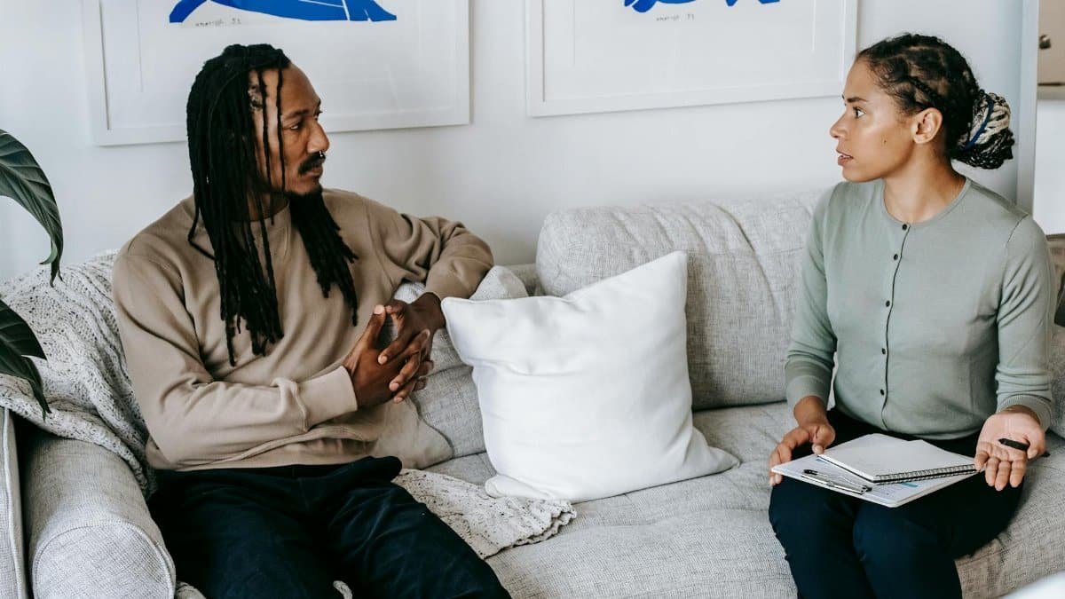 Professional therapy session indoors, with two adults focused on discussion and support.