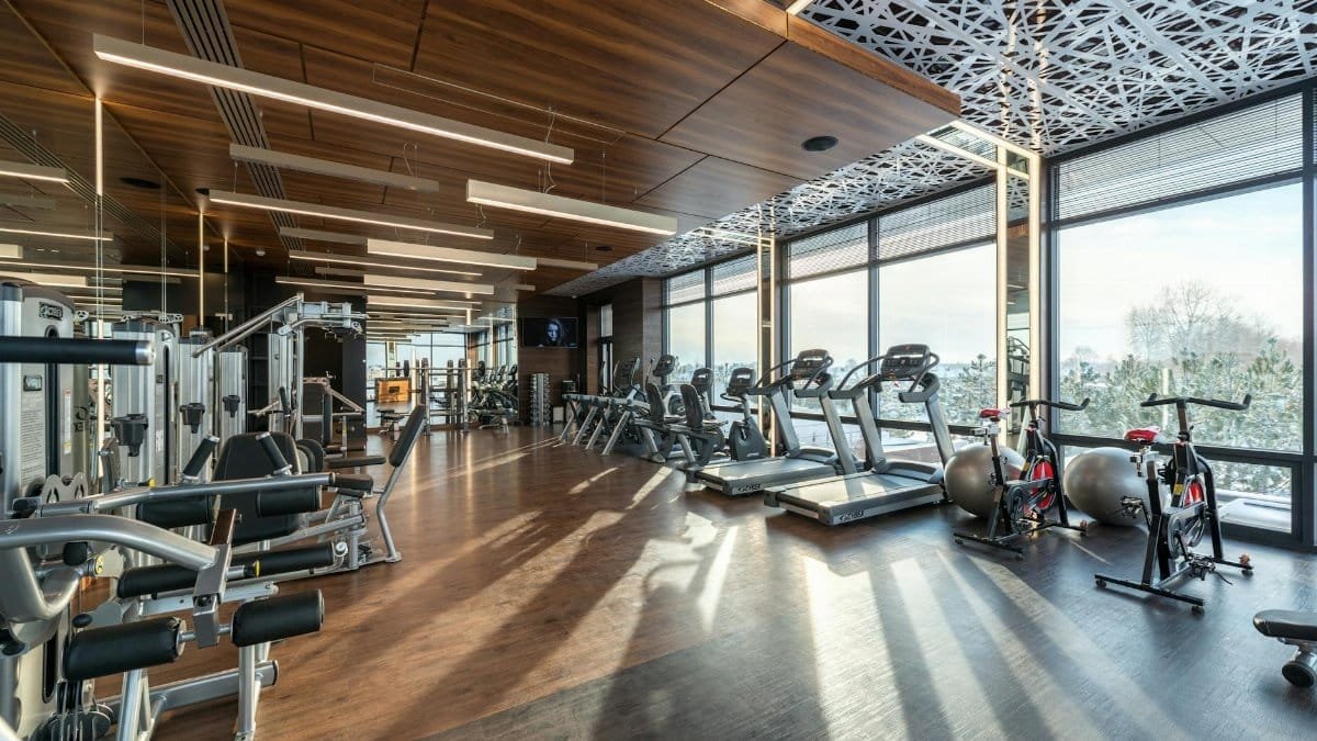 Spacious modern gym with treadmills, exercise bikes, and weights under natural lighting.