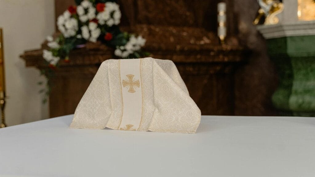A beautifully detailed altar cloth displayed on an ornate church table, surrounded by floral arrangements.