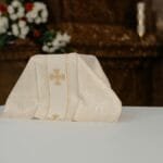 A beautifully detailed altar cloth displayed on an ornate church table, surrounded by floral arrangements.
