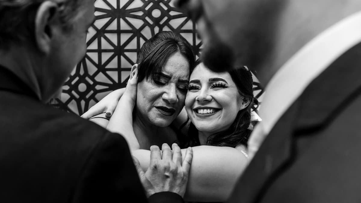 A joyful wedding moment with family embracing in black and white.
