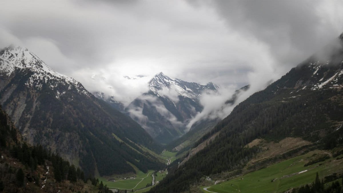 Dramatic view of the snow-capped Alps and lush valley in Zillergrund, Austria.